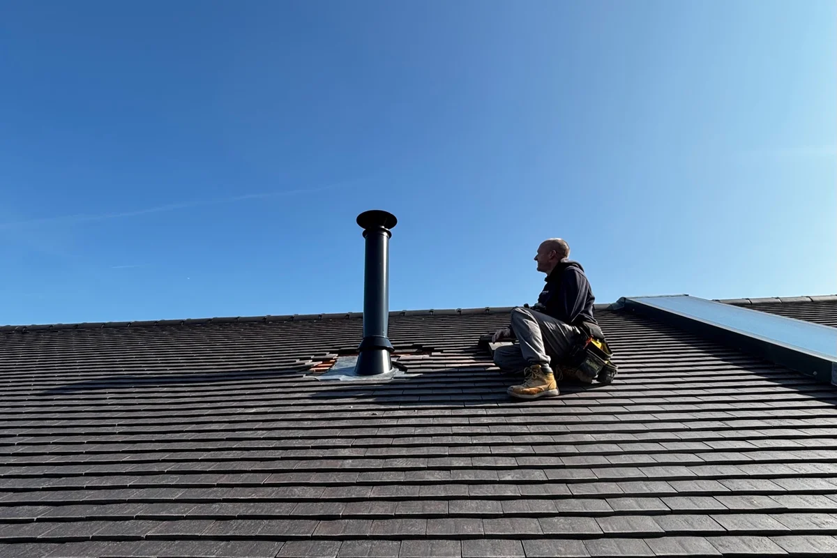 Chimney engineer installing external flue system on roof in Kent